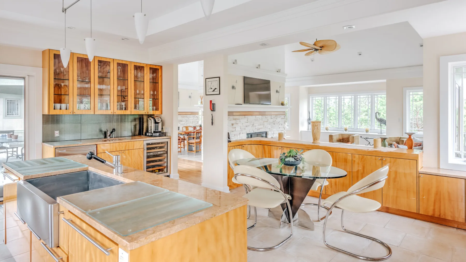 A bright kitchen and dining area with wood cabinetry and a glass dining table.