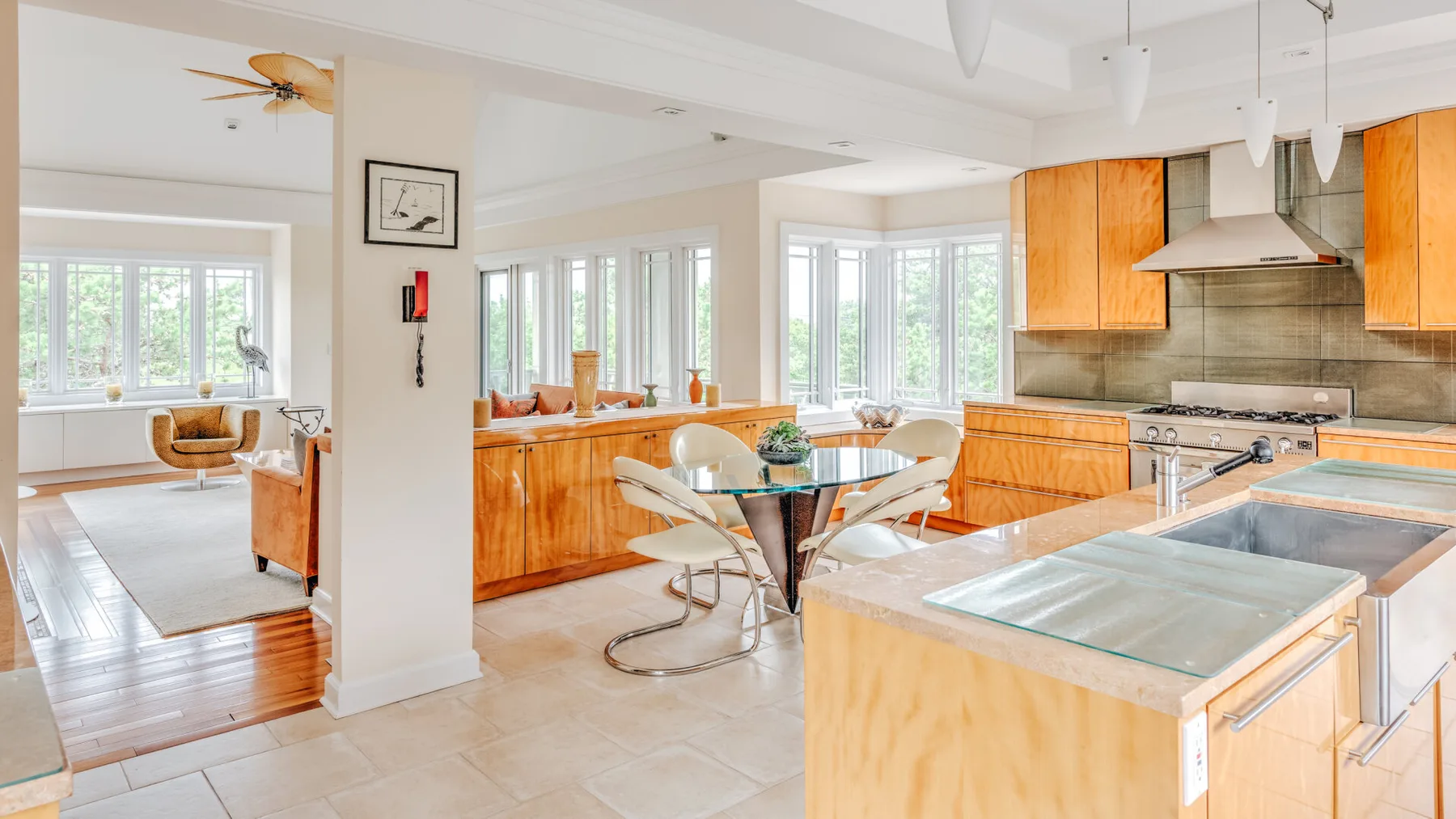 An open-plan kitchen and dining area with a central island and glass dining table.