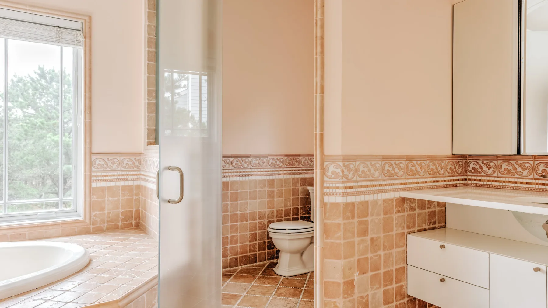 A tiled bathroom with a bathtub, toilet, and vanity.