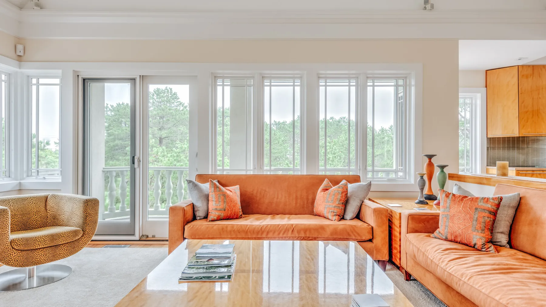 A bright living room with orange seating and large windows.