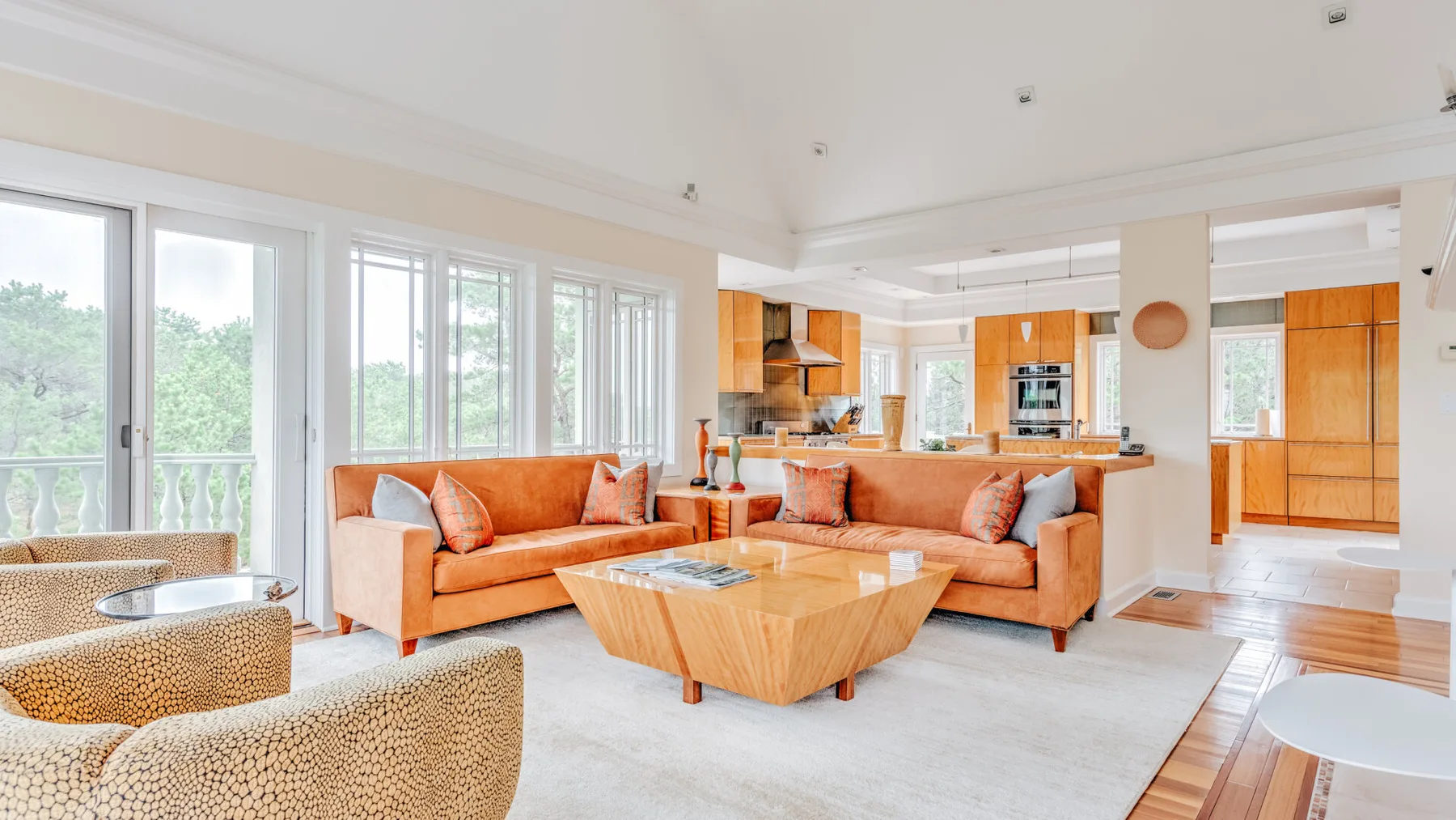 A bright open-plan living room with orange seating and a wooden coffee table.
