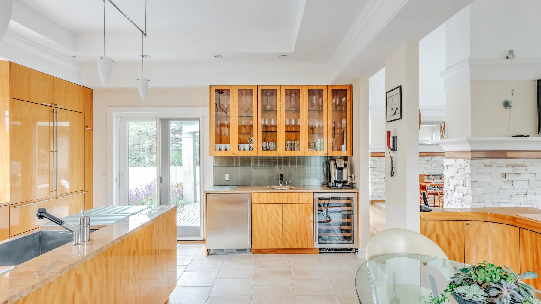 A bright kitchen with wood cabinetry, a tiled backsplash, and a dining table.