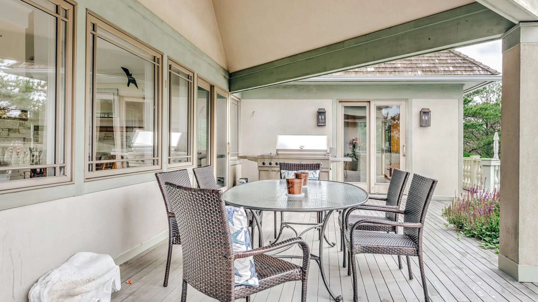 A covered outdoor dining area with a round table and woven seating.