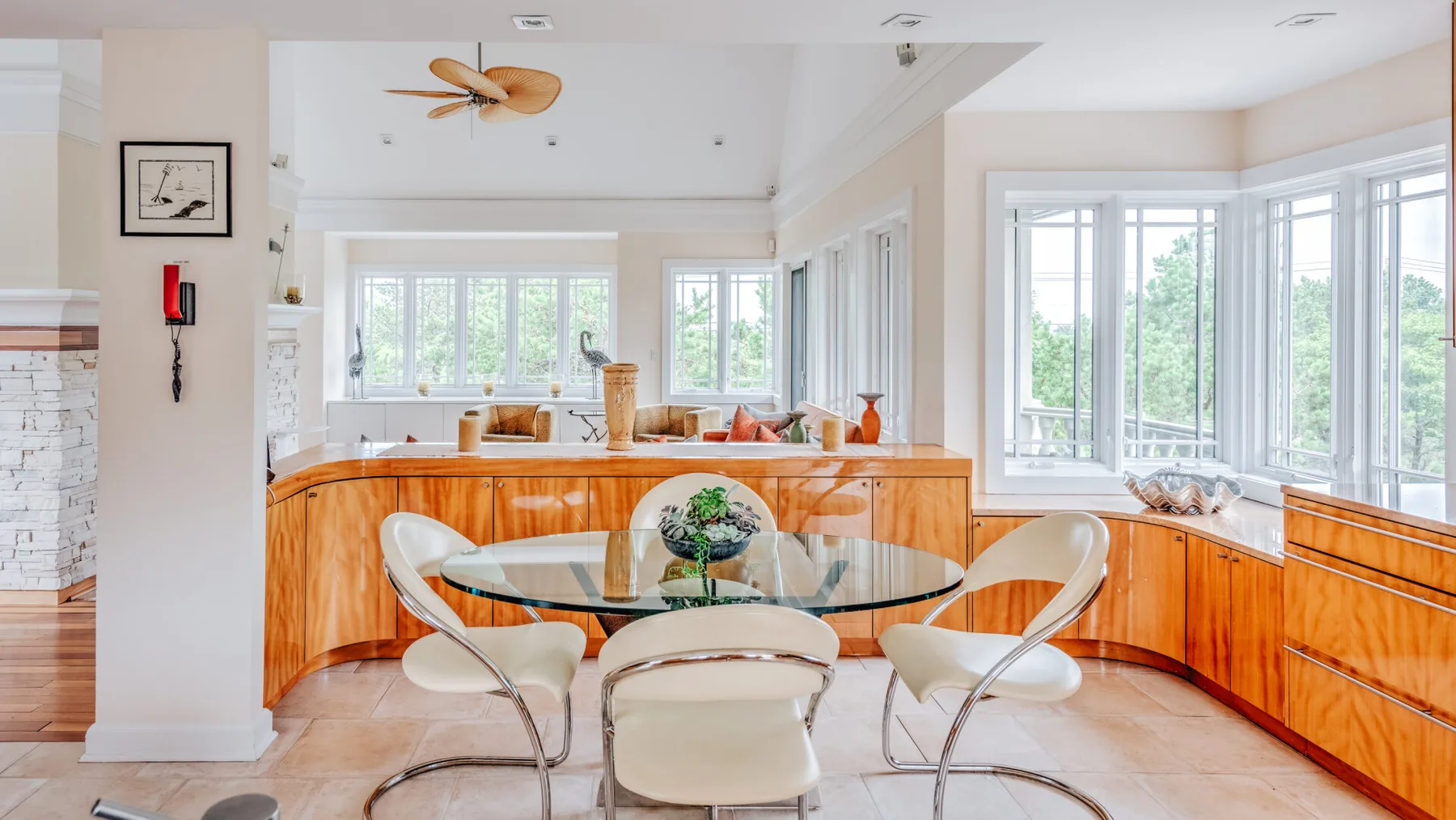 A bright kitchen with curved wooden cabinetry and a glass dining table.