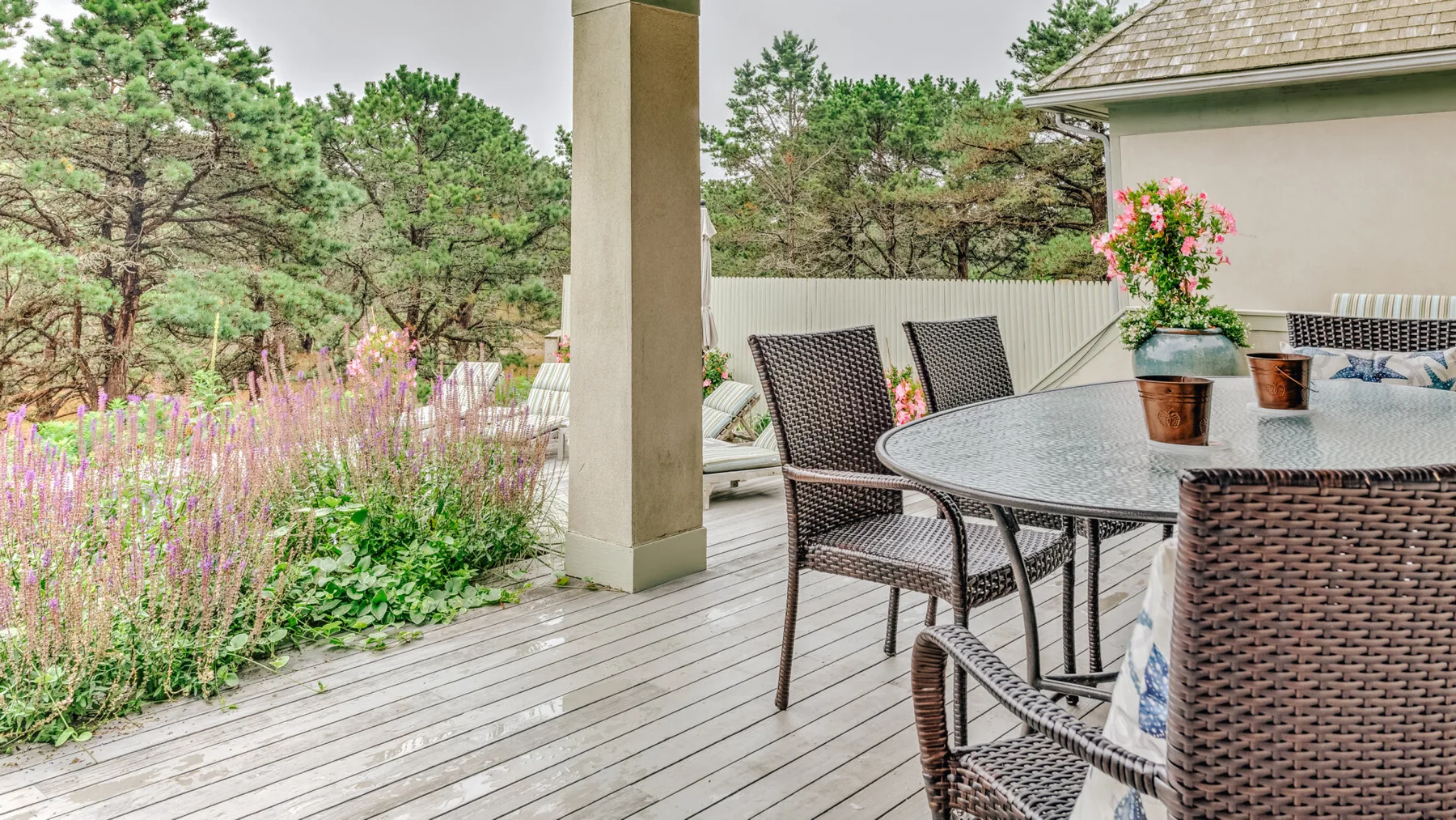 A furnished outdoor patio with a round table and garden views.