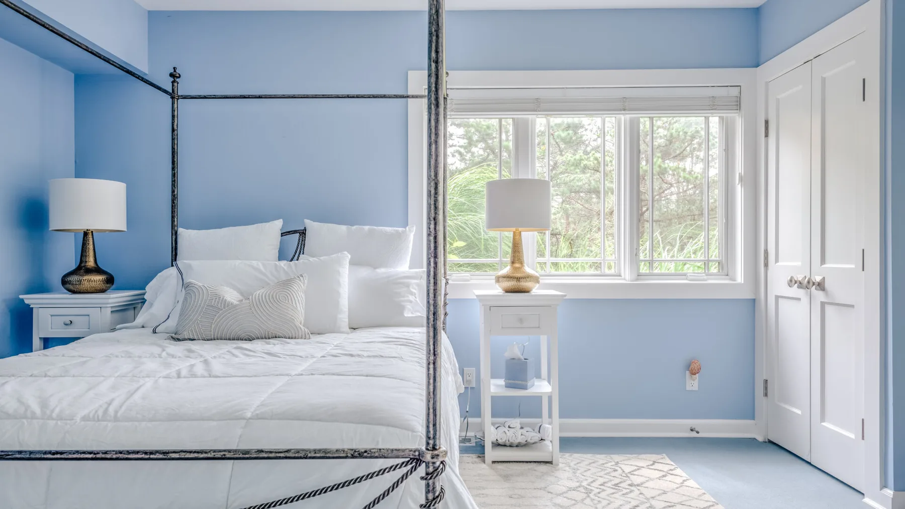 A bright bedroom with a neatly made bed beside a large window.