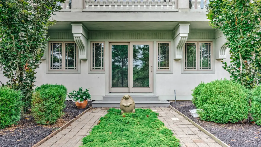A garden path leads to the windows and entrance of a house.
