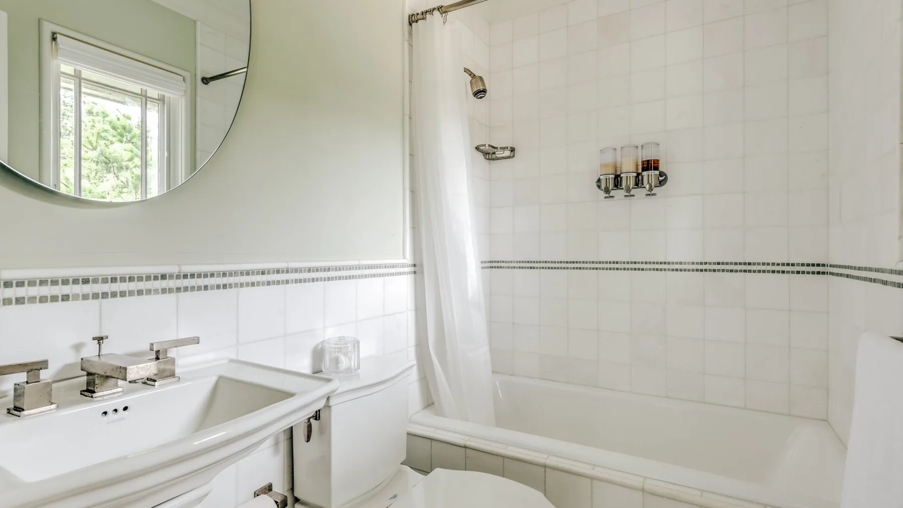 A bright tiled bathroom with a bathtub, shower curtain, and sink.