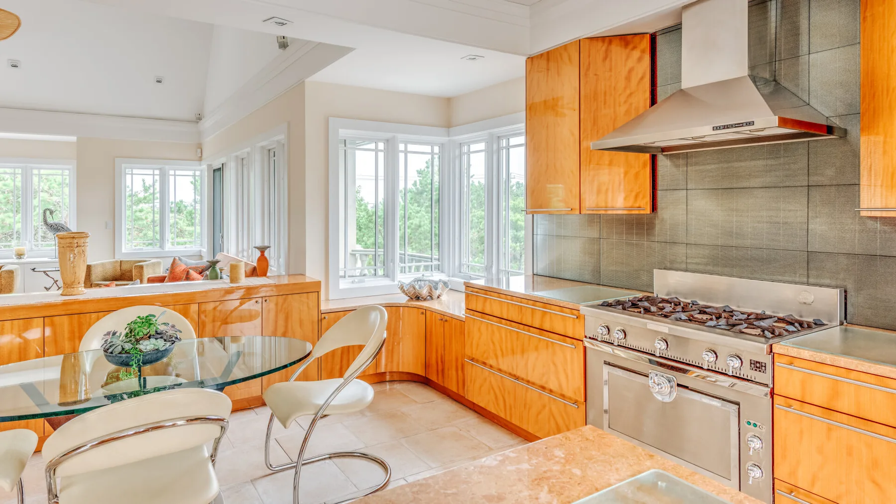 A bright kitchen with wooden cabinetry, a gas cooktop, and a glass dining table.