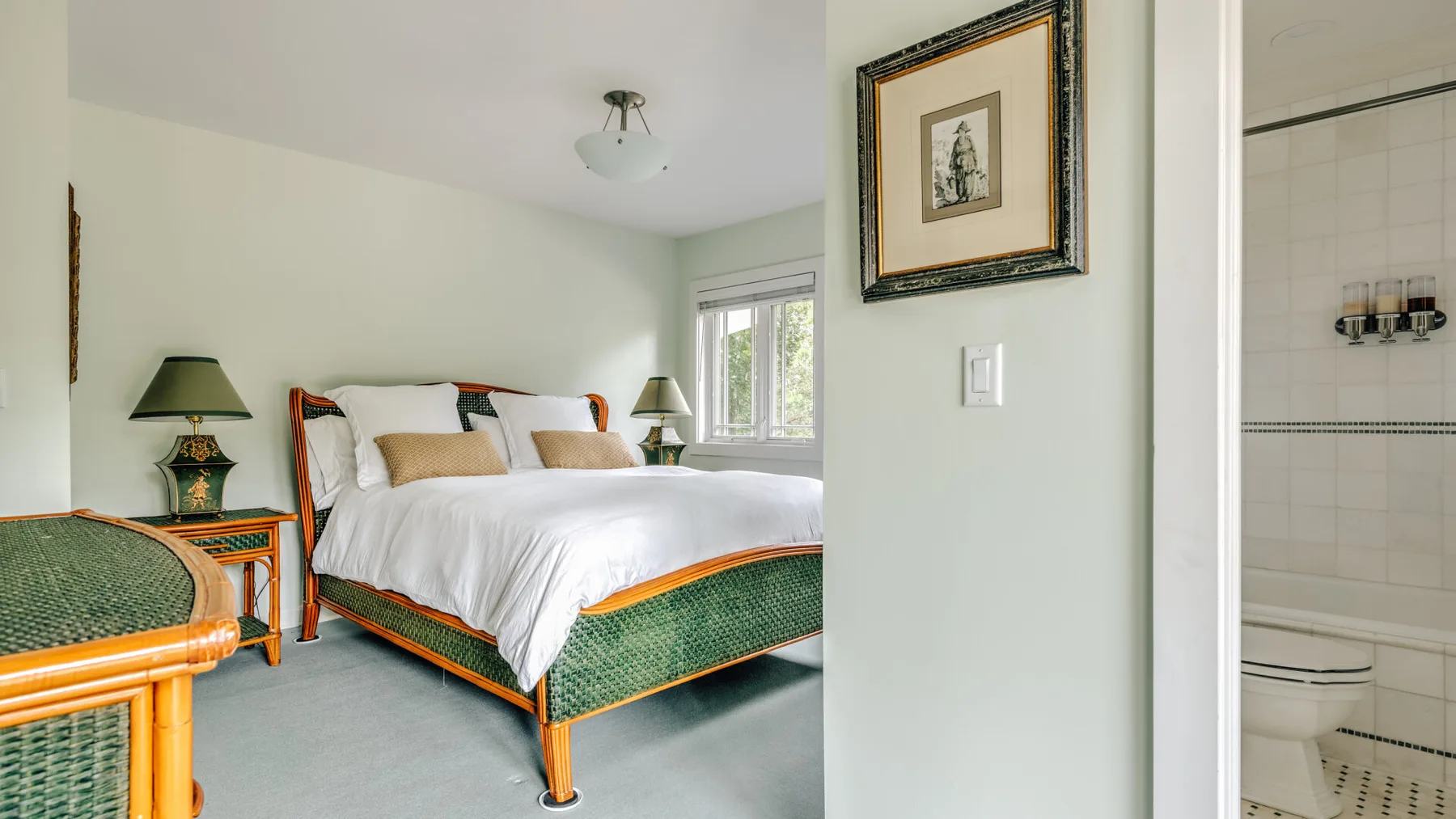 A bedroom with a white bed and green patterned bedding.