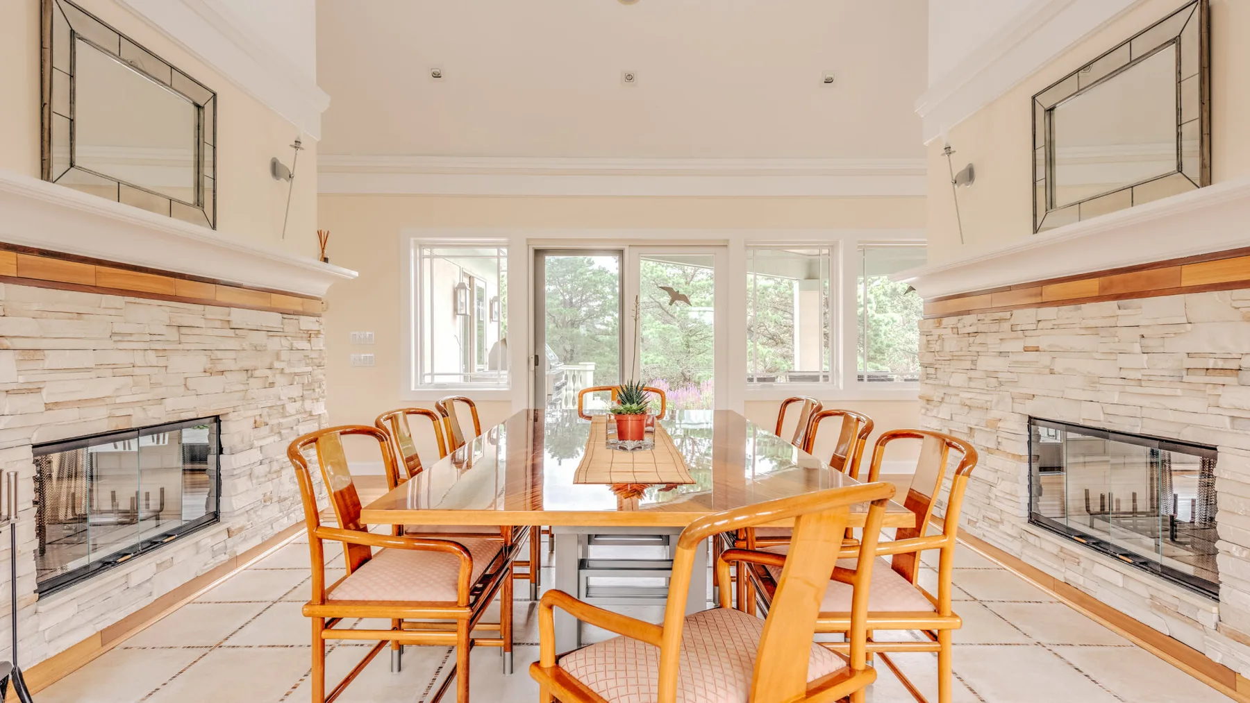 A bright dining area with a long table and chairs between two fireplaces.