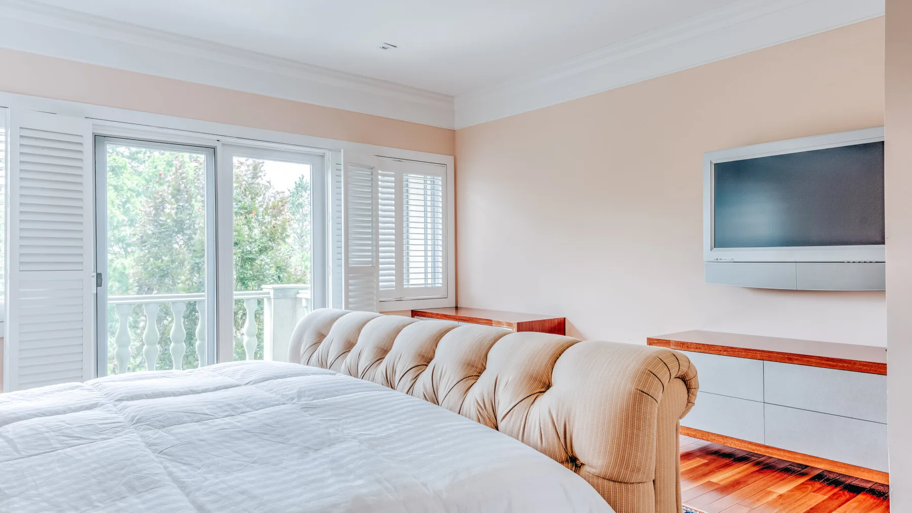 A bedroom with a bed, upholstered seating, and a wall-mounted television.