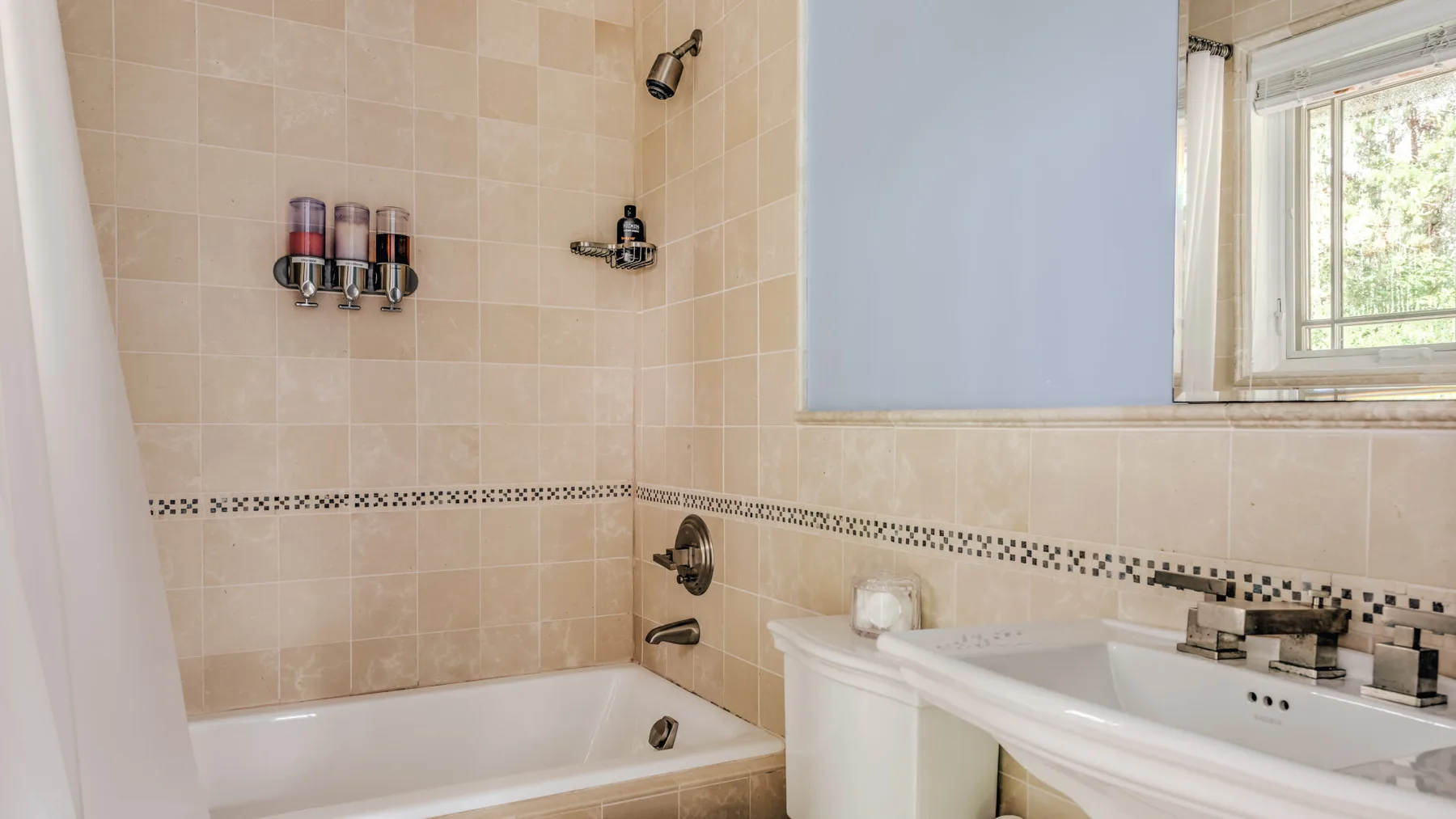 A tiled bathroom with a bathtub, shower fixtures, and a window.