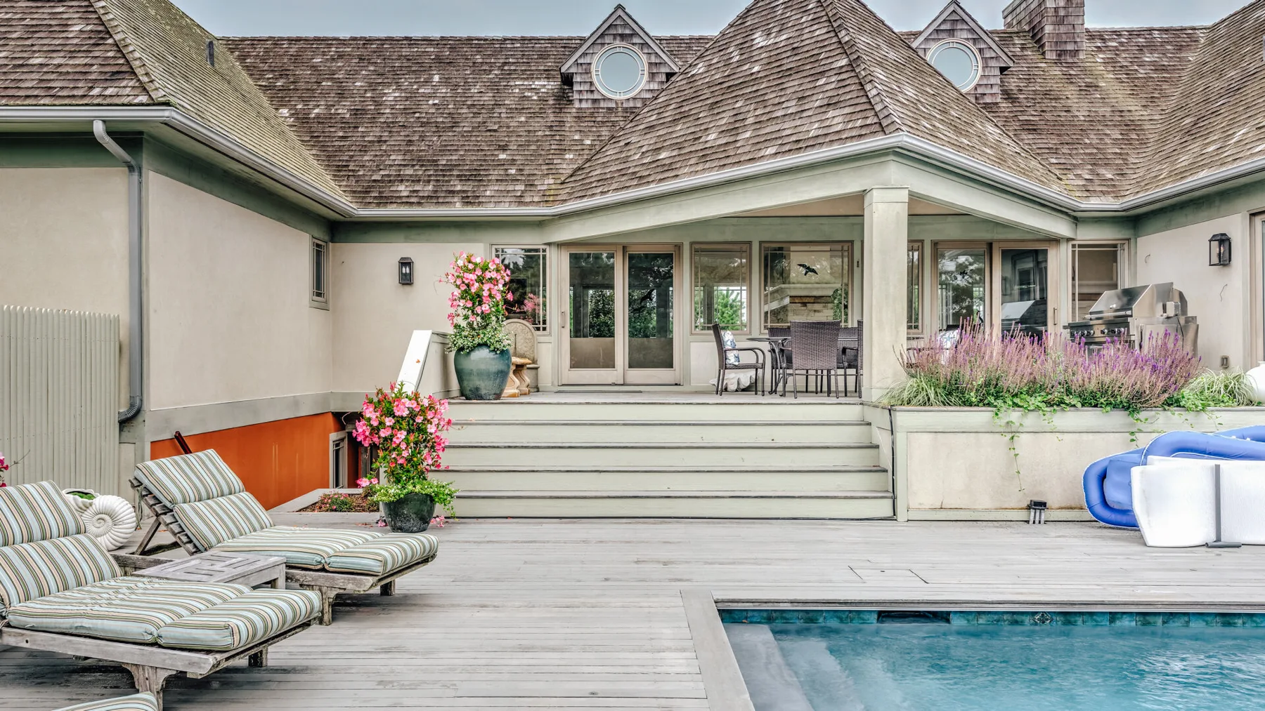 A house patio with seating, steps, and a swimming pool.