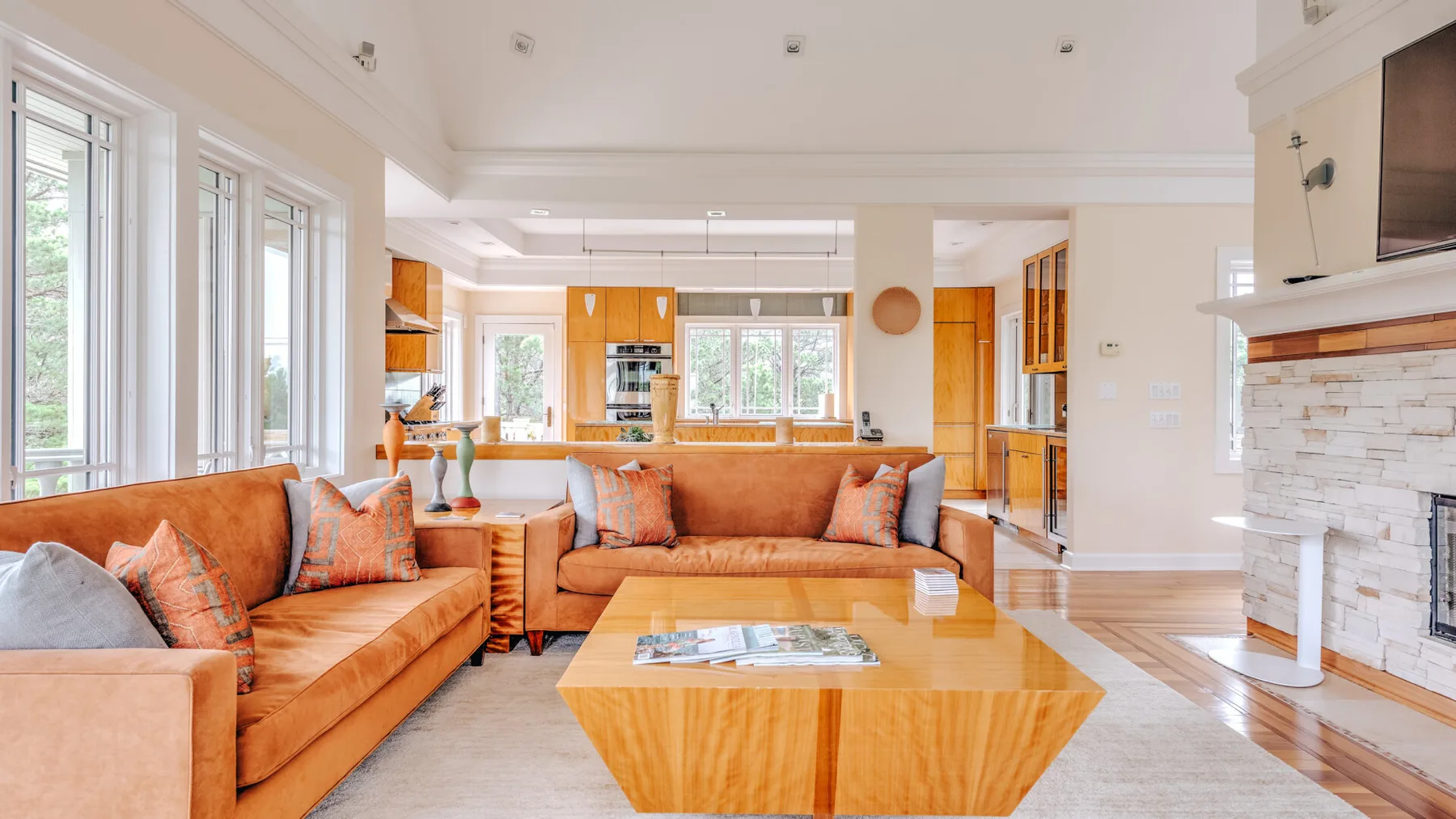 A bright living room with orange seating, a coffee table, and a fireplace.
