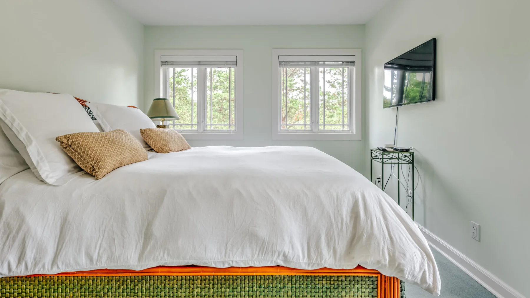 A bright bedroom with a large bed and two windows.
