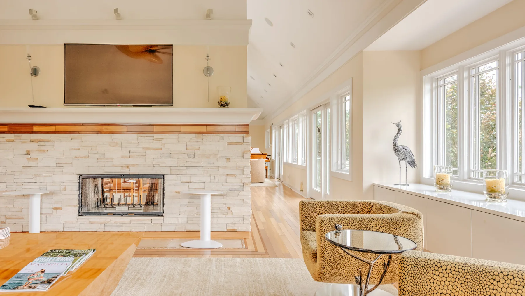 A bright living room with a fireplace, seating, and large windows.