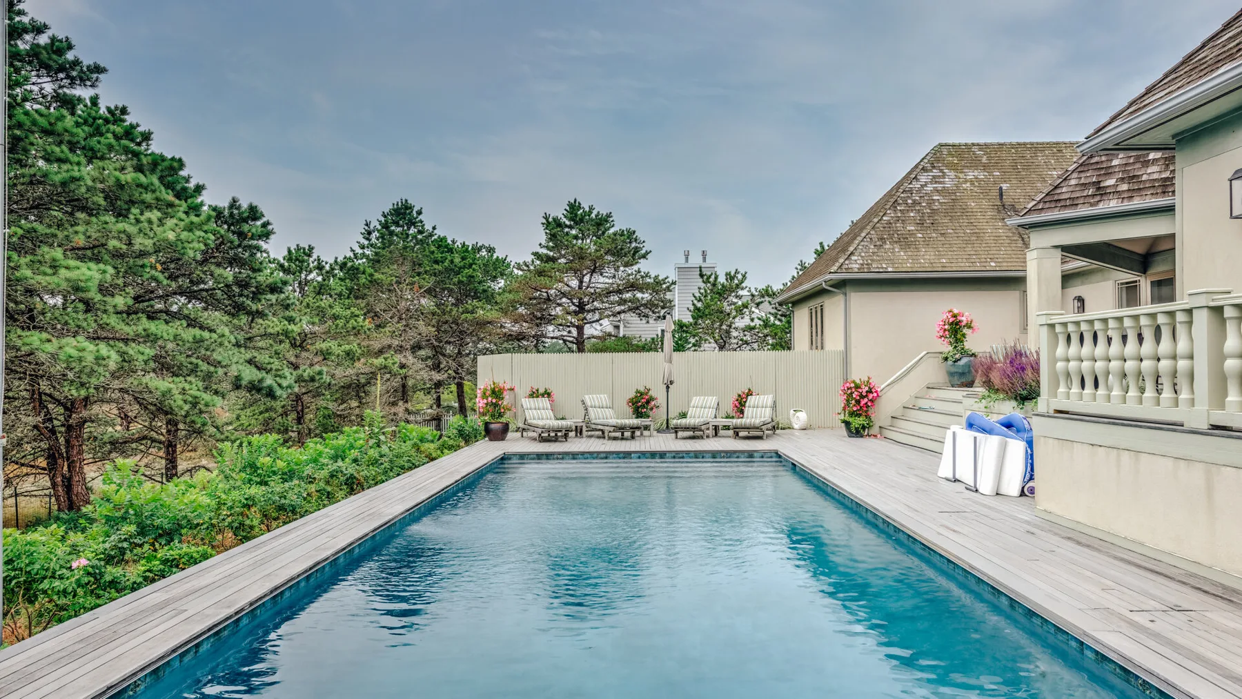 An outdoor swimming pool is bordered by a deck and trees.