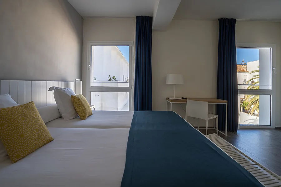Hotel room with twin beds and windows.