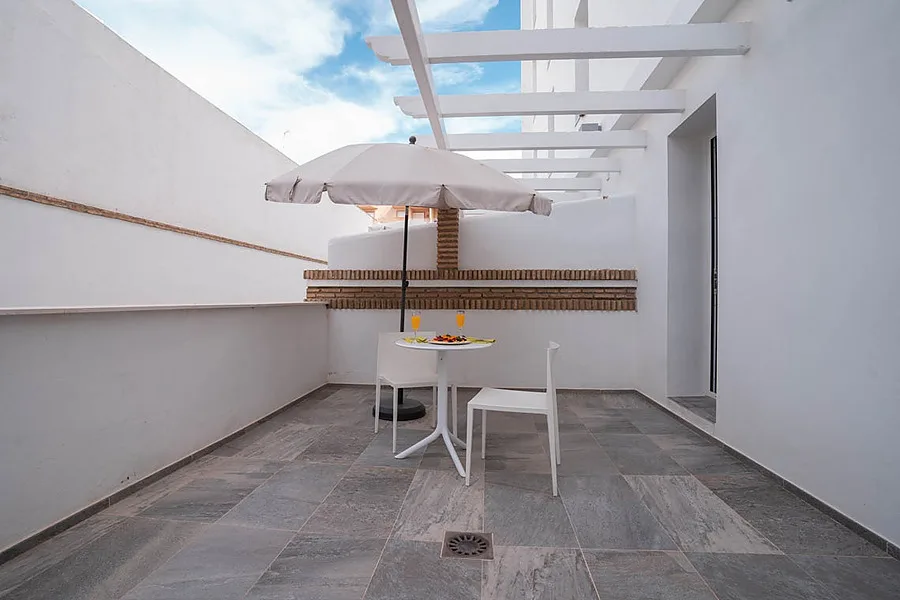 Outdoor hotel terrace with table and chairs.