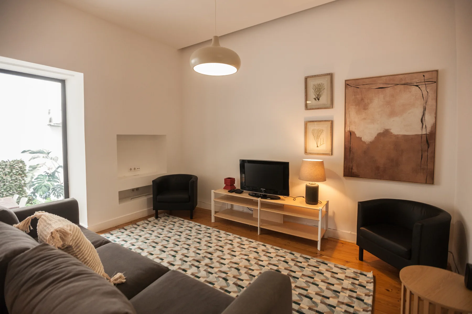 Una sala de estar con asientos, un televisor y cuadros enmarcados.