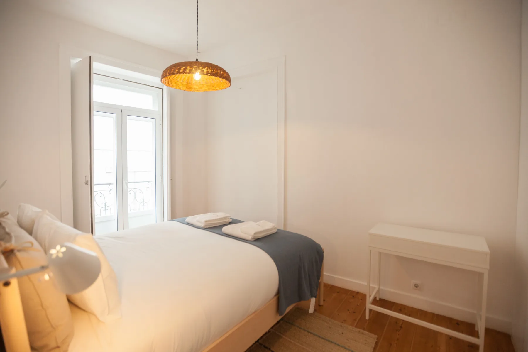 Un dormitorio luminoso con una cama bien tendida y una lámpara colgante.