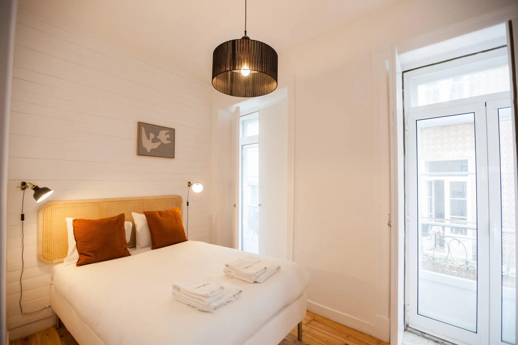 Un dormitorio luminoso con una cama bien tendida y una puerta de cristal.