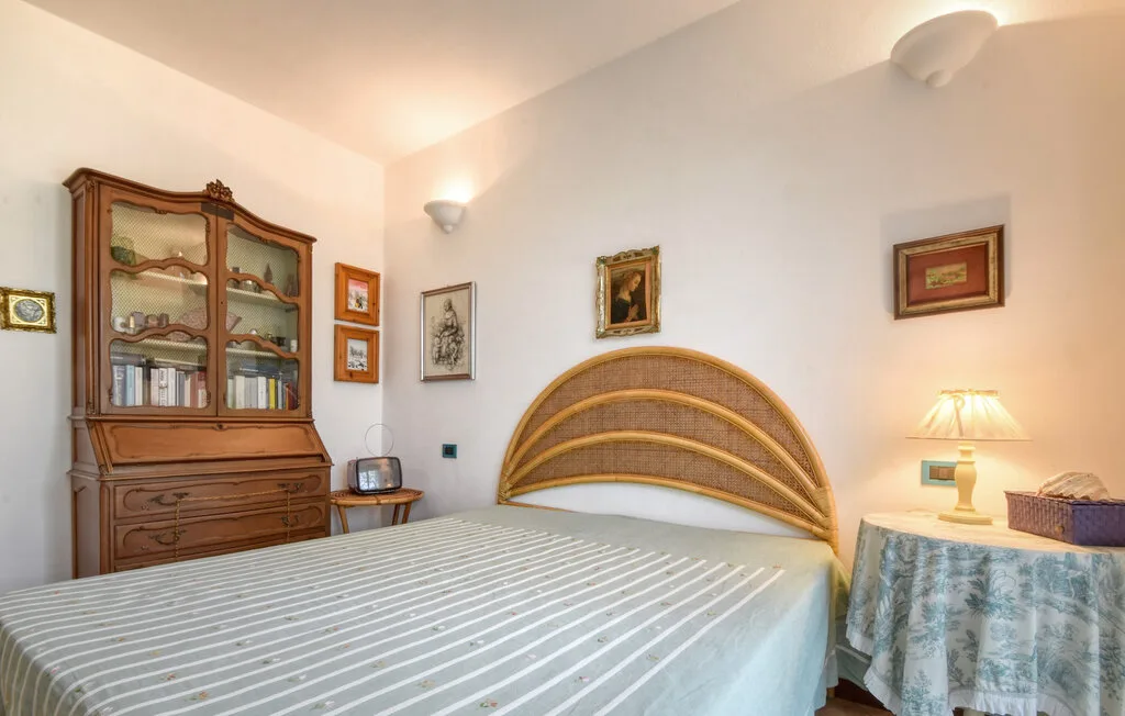 Un dormitorio con una cama bien tendida y un mueble de madera junto a la pared.