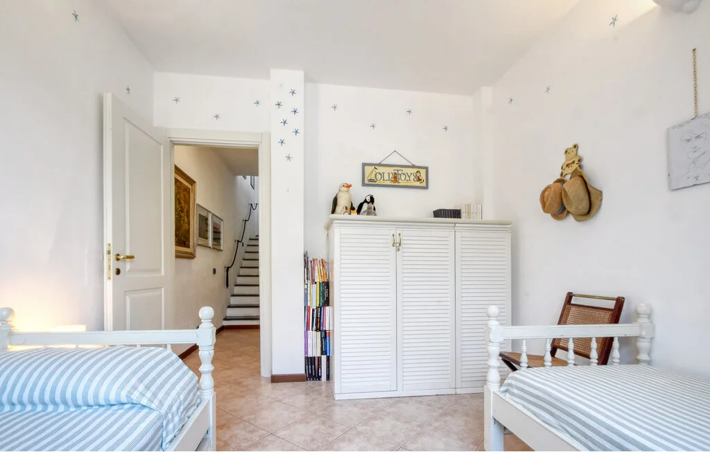Un dormitorio luminoso con dos camas y un armario blanco.