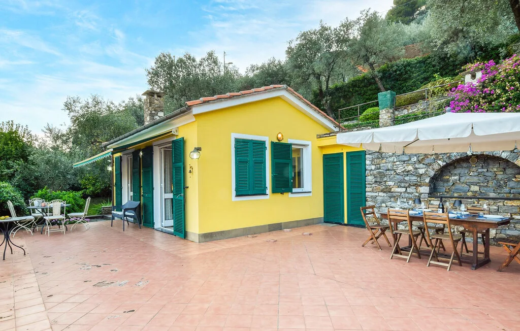 Una casa amarilla da a un patio embaldosado con mesas de comedor al aire libre.