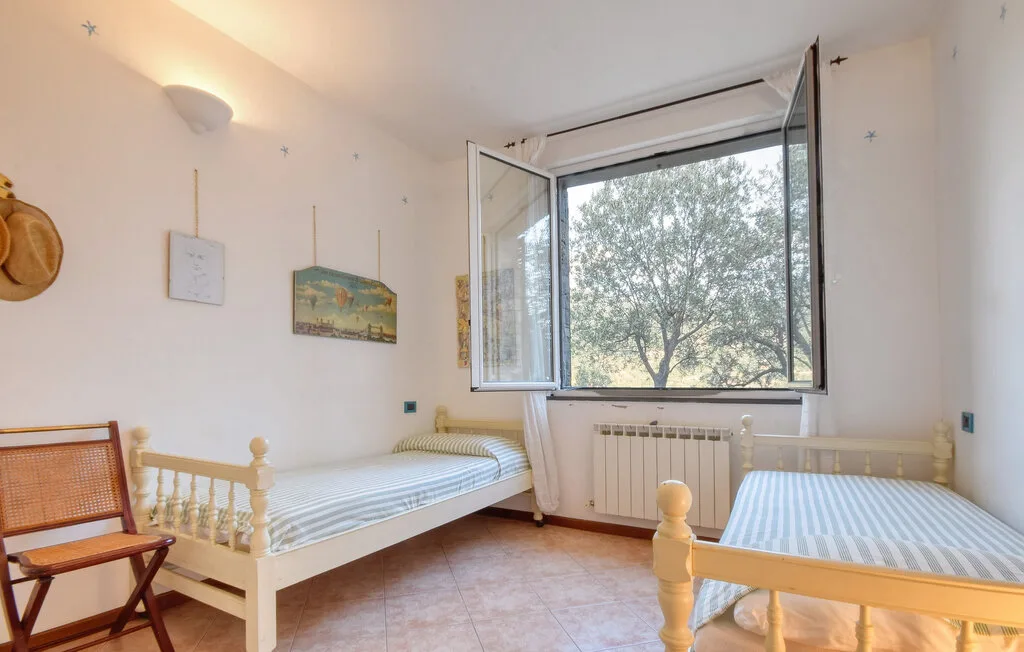 Un dormitorio con dos camas individuales junto a una ventana abierta.