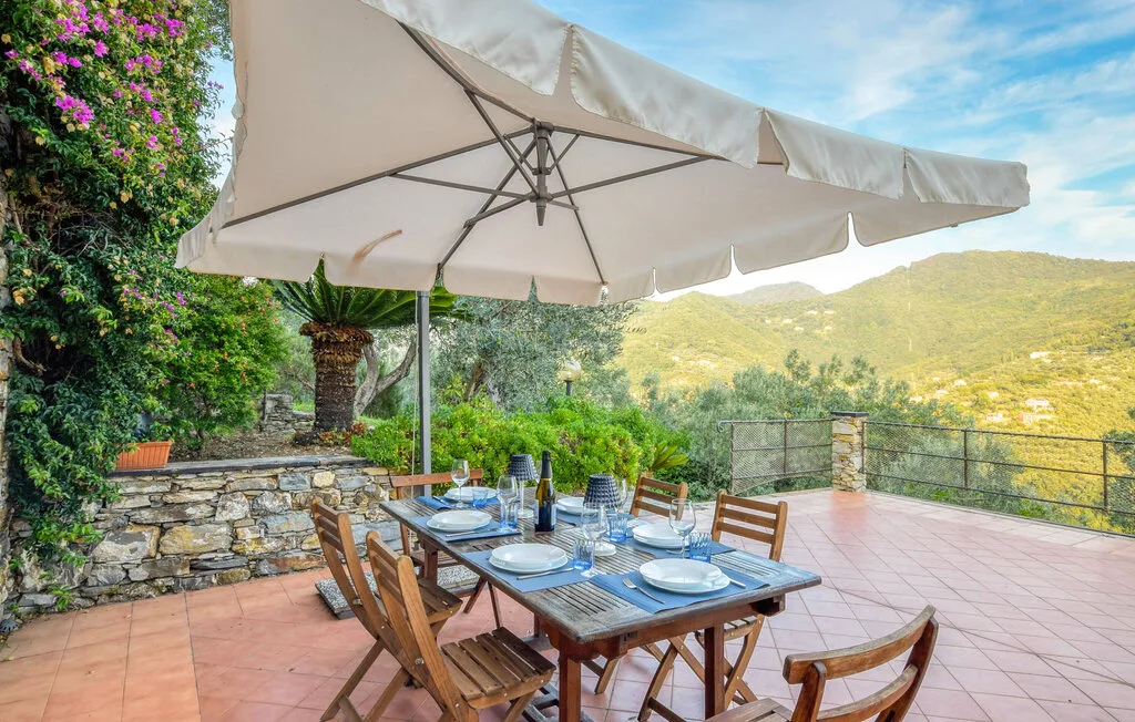 Un patio al aire libre con una mesa puesta bajo una gran sombrilla.