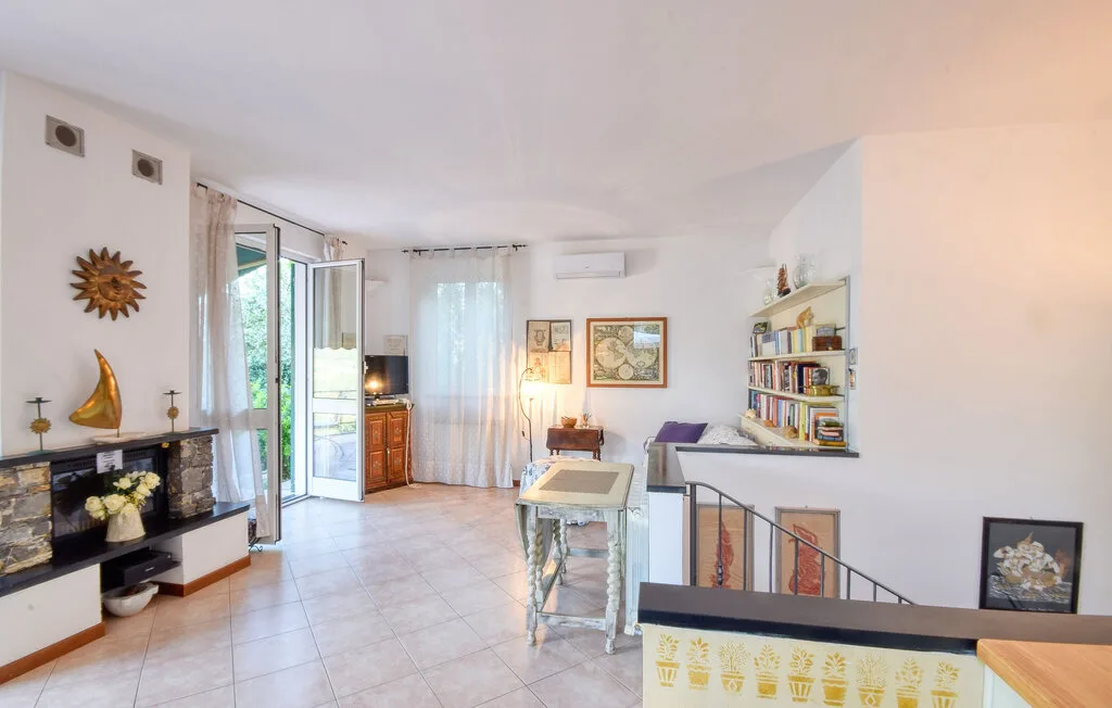 Una sala luminosa con asientos, una estantería y una puerta abierta al balcón.
