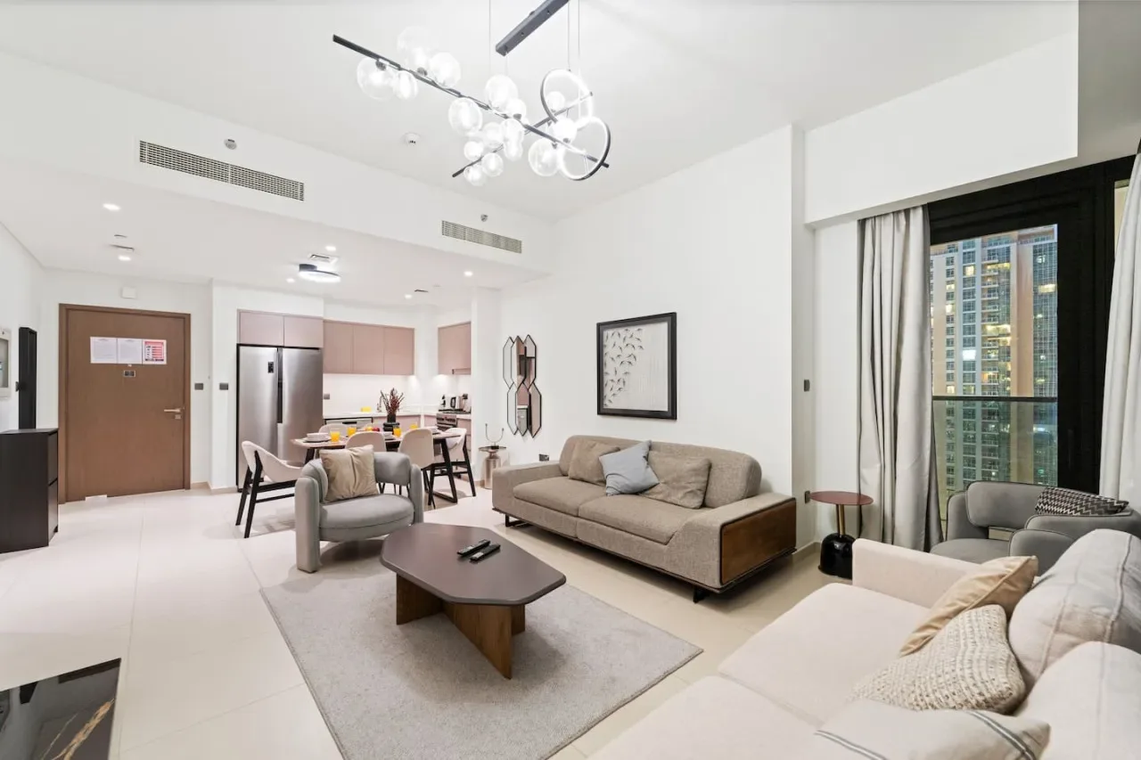 A bright living room with seating, a coffee table, and an open dining area.