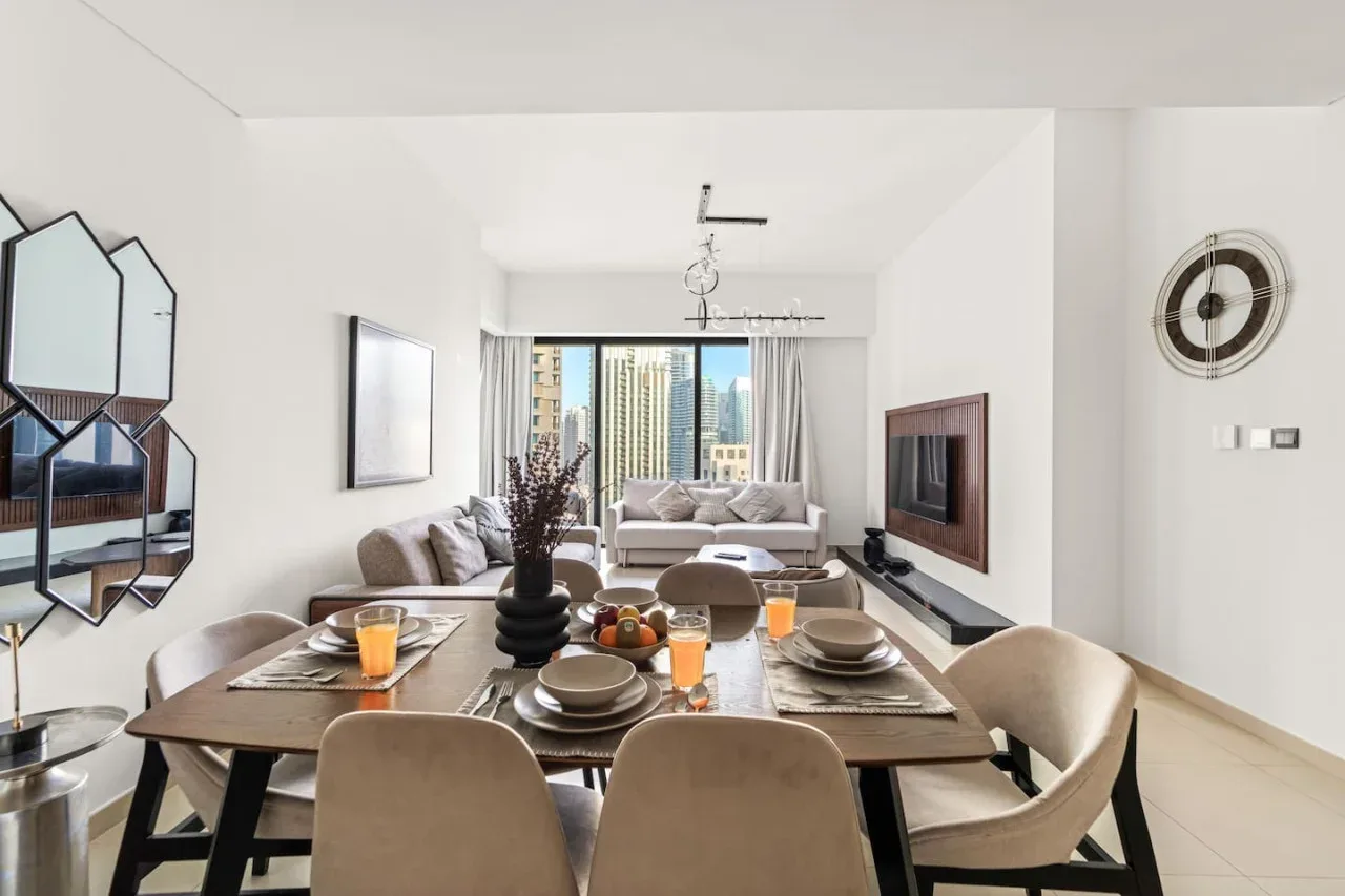 Una luminosa sala de estar y comedor con una mesa puesta junto a una gran ventana.