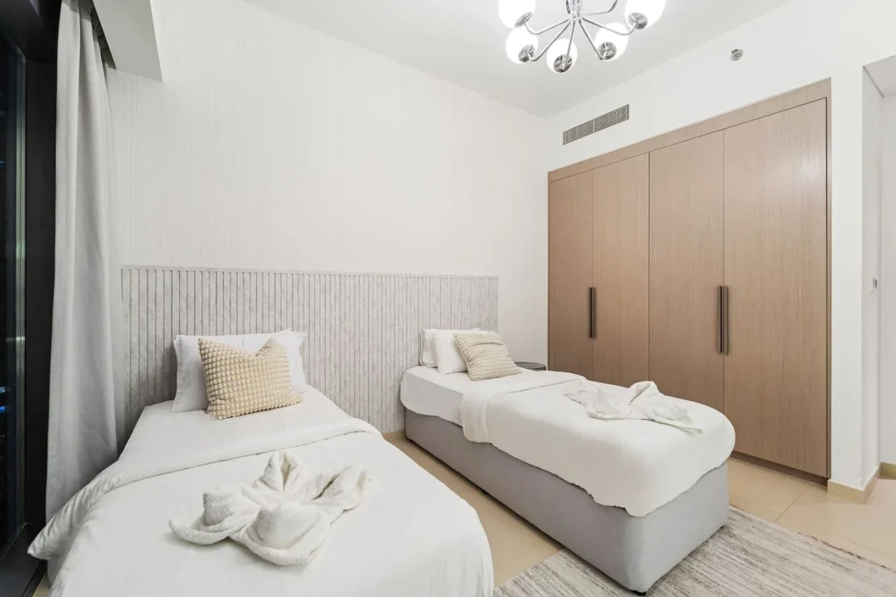 Un dormitorio luminoso con dos camas y un armario grande.