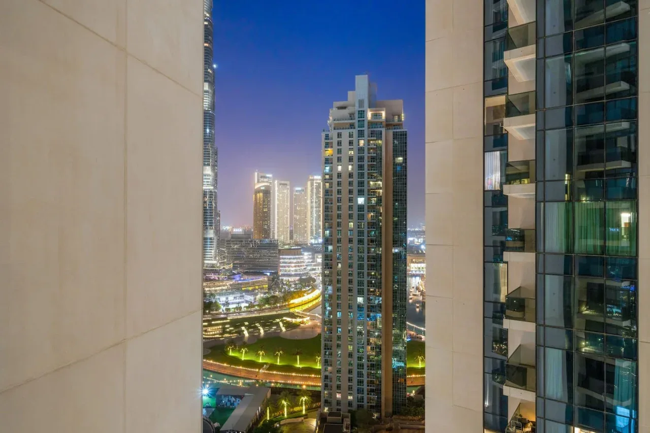Un horizonte urbano nocturno visto entre edificios modernos de gran altura.