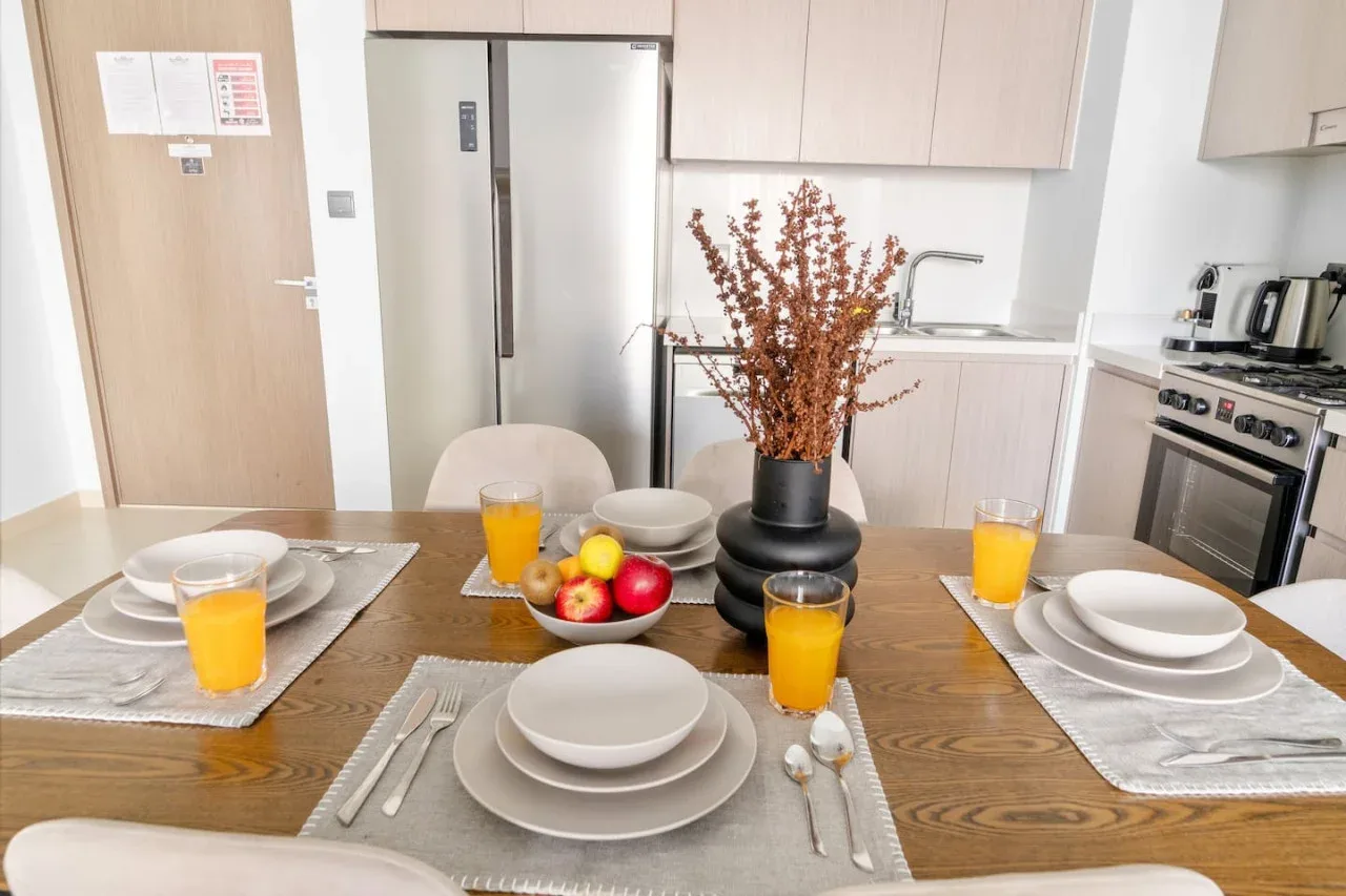 Una mesa está puesta con platos y bebidas en una cocina luminosa.