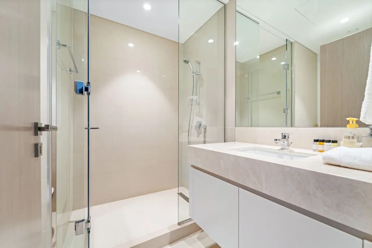 Un baño luminoso con una ducha de vidrio y un amplio lavabo.