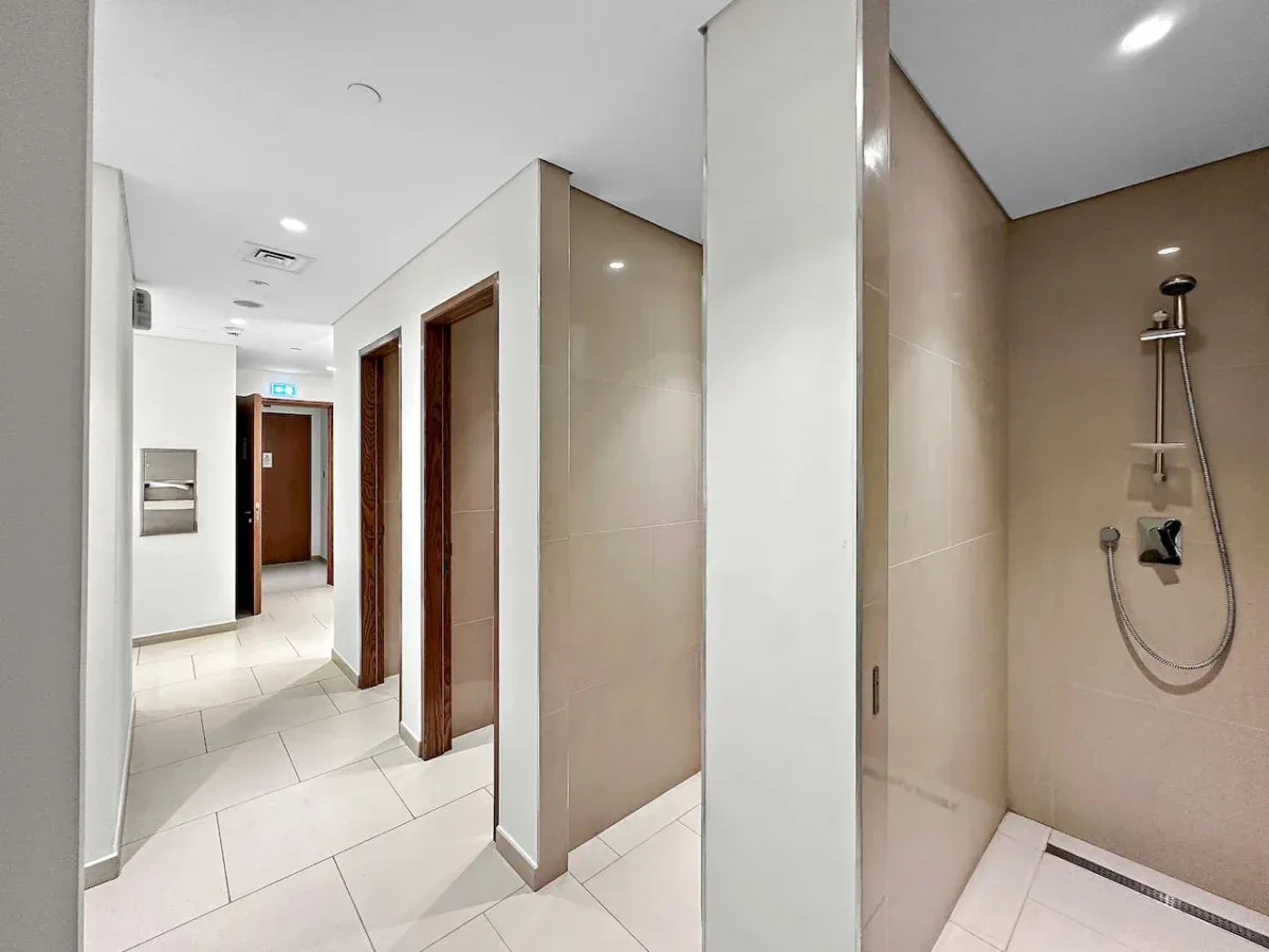 Un pasillo de baño con azulejos, varias puertas y una zona de ducha.