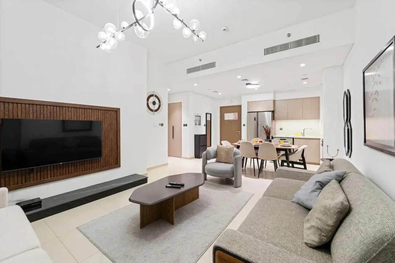 Una sala luminosa con asientos, un televisor y un comedor abierto.