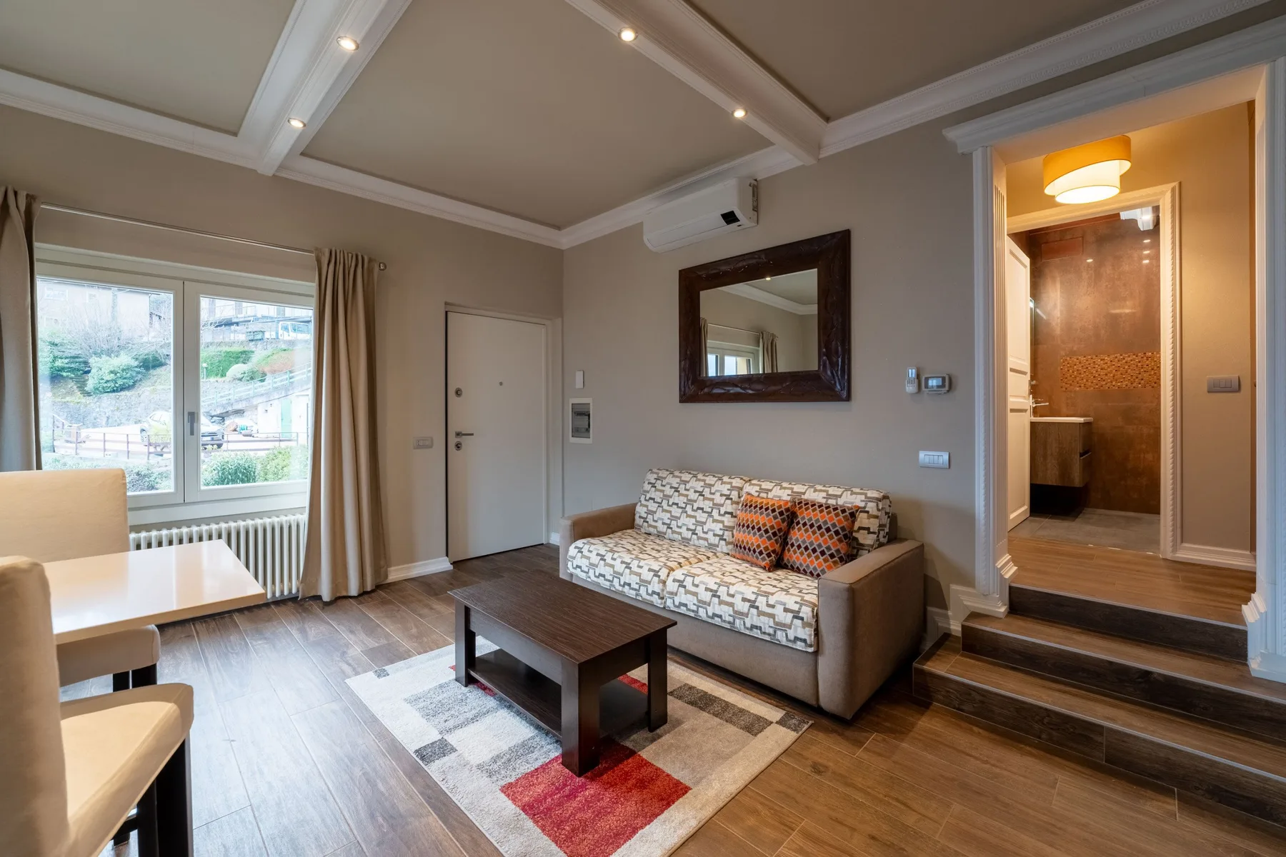 Una sala de estar con sofá, mesa de centro y ventanas grandes.