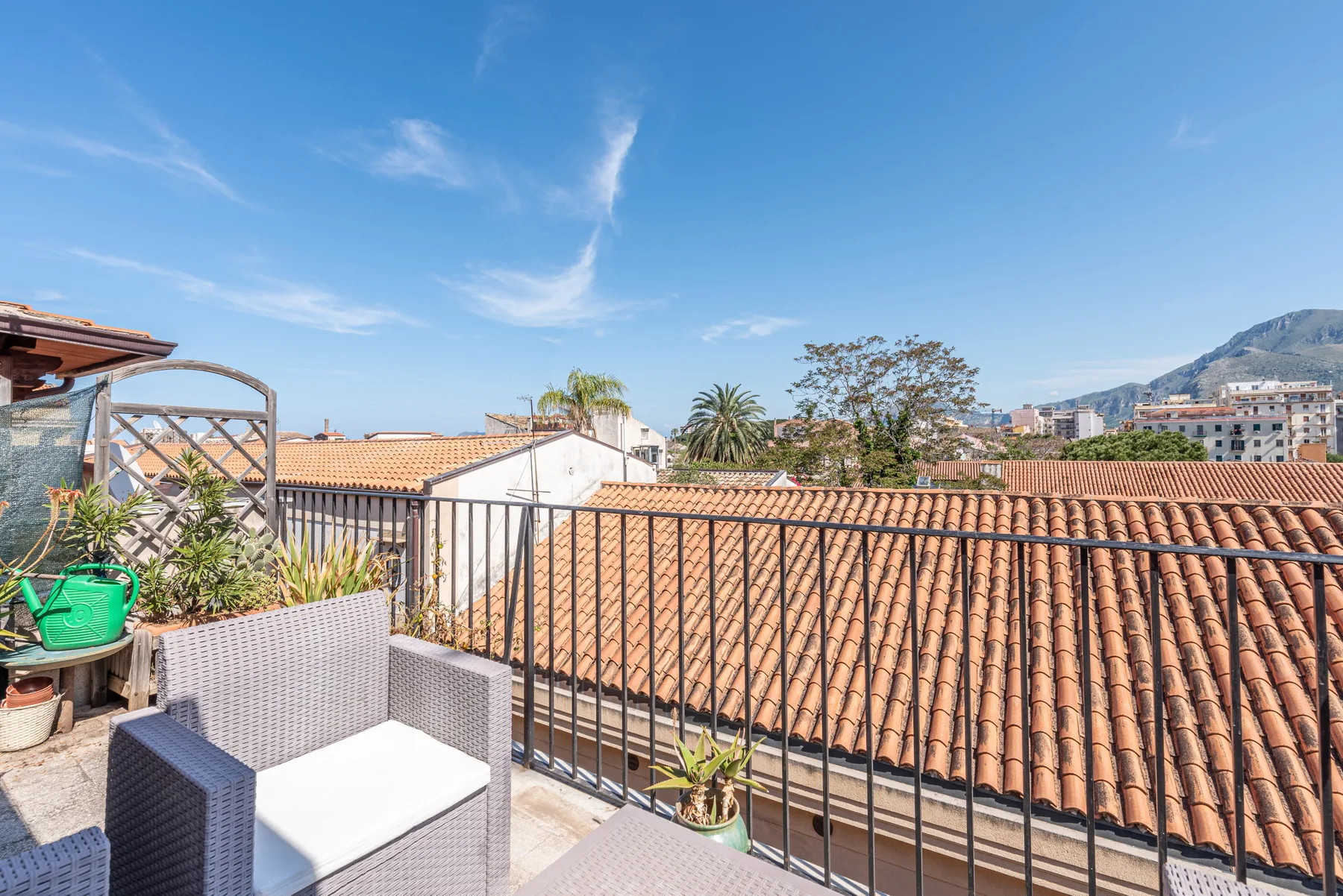 Una terraza en la azotea da a tejados de terracota, con asientos junto a una barandilla metálica.