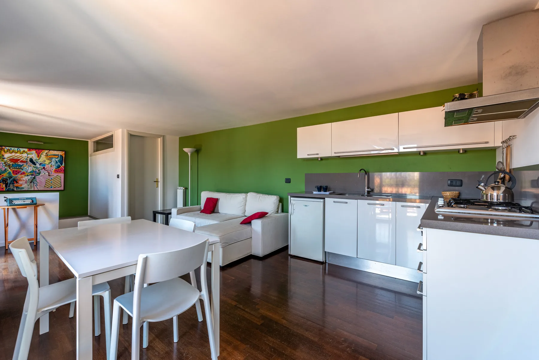 Una sala y cocina de concepto abierto con mesa de comedor y asientos blancos.