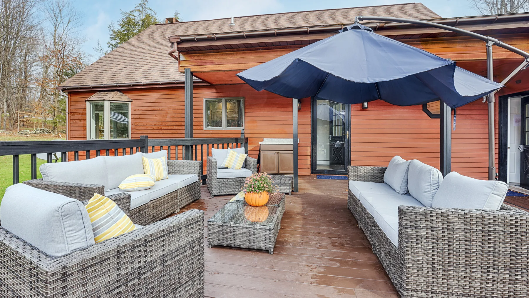 An outdoor patio seating area with cushioned wicker furniture and a large umbrella.