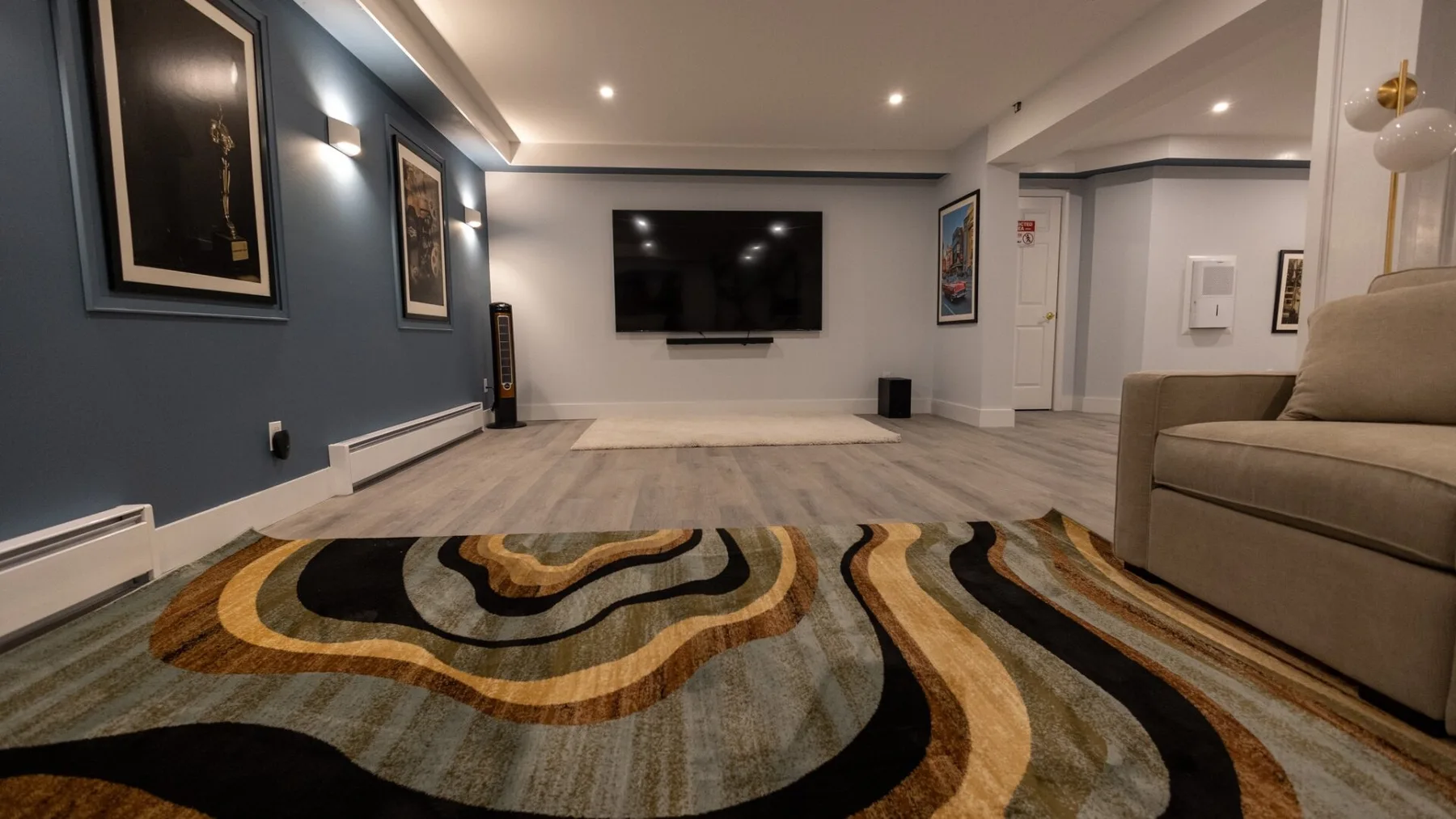 A living room with a wall-mounted television and a patterned rug.