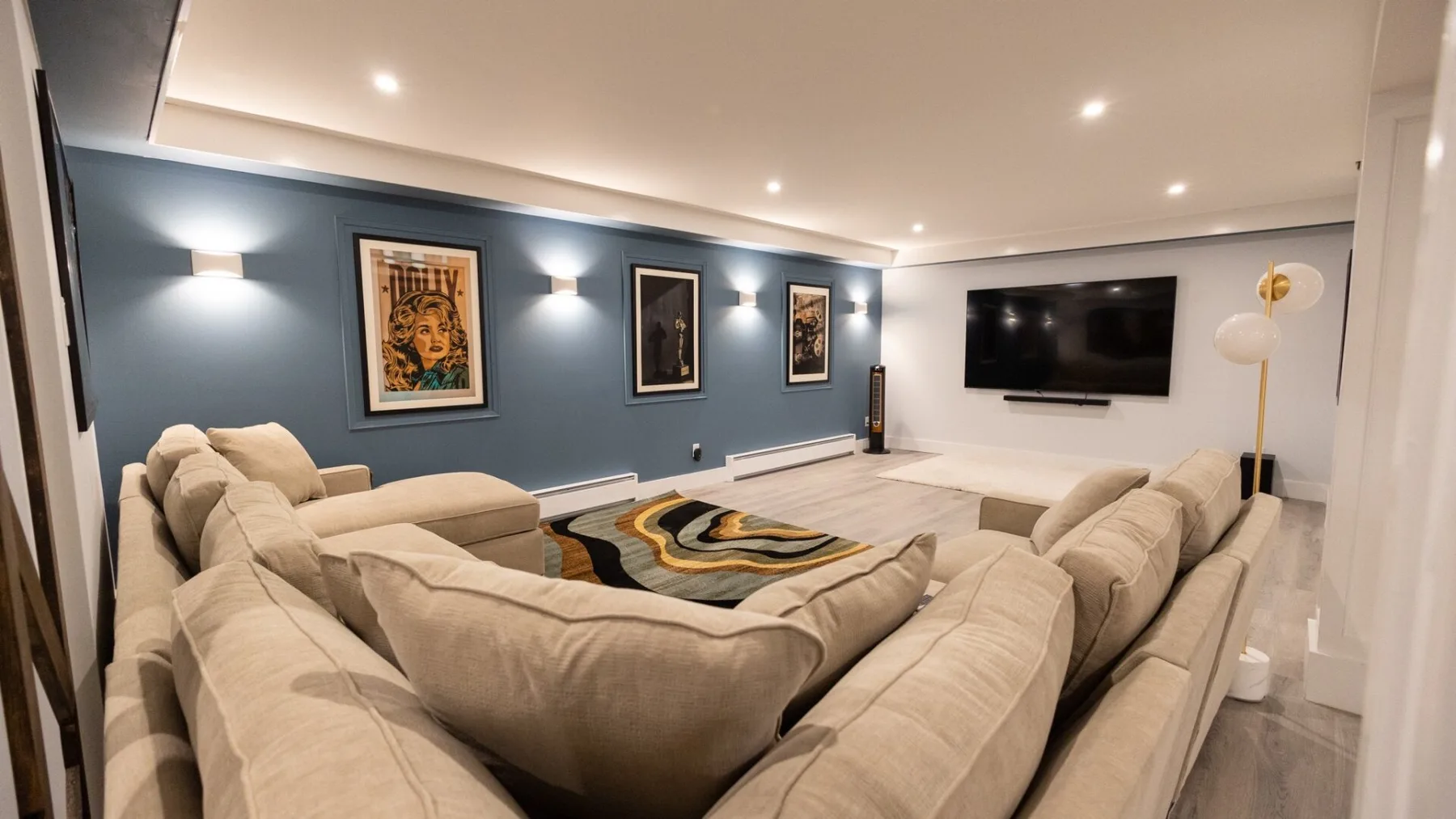 A living room with a large sectional seating area and a wall-mounted television.
