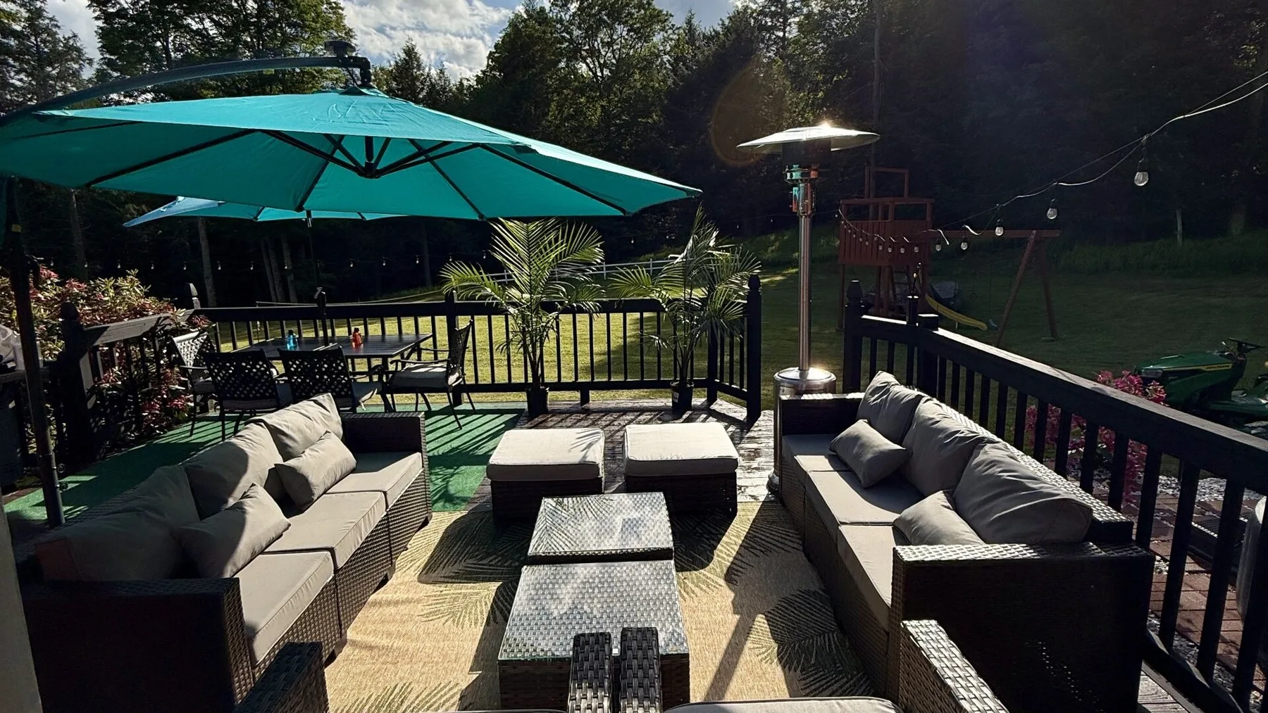 An outdoor deck with seating beneath a large turquoise umbrella.
