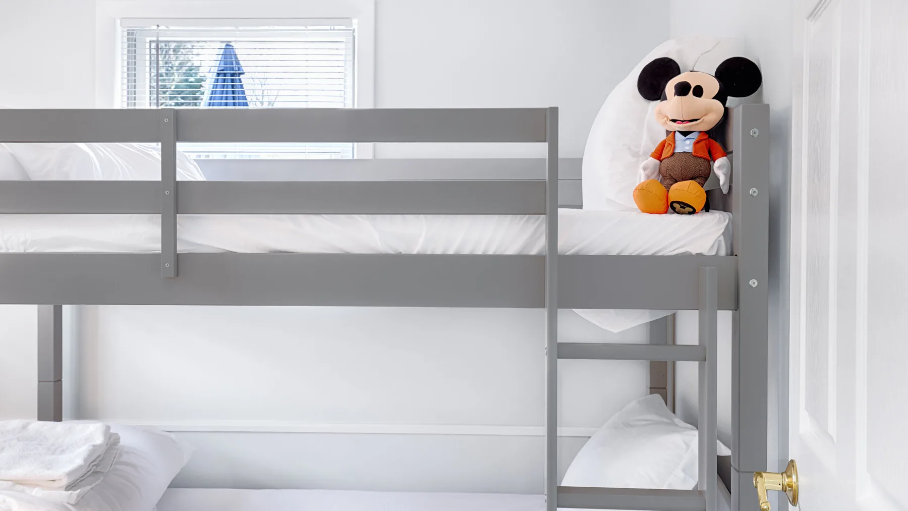 A bedroom with a gray bunk bed and a character plush toy.