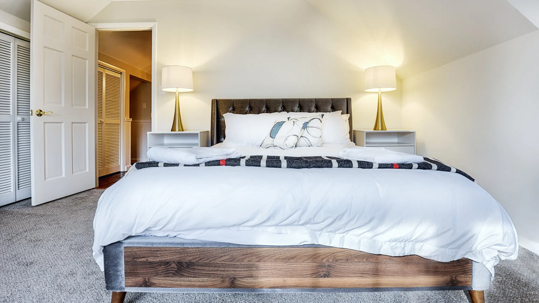 A bedroom with a large bed, white bedding, and matching bedside lamps.